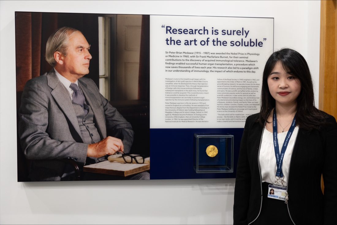 Dr Yiqi Zhao alongside Peter Medawar’s Nobel Prize medal, on display in the Medawar Building, University of Oxford.